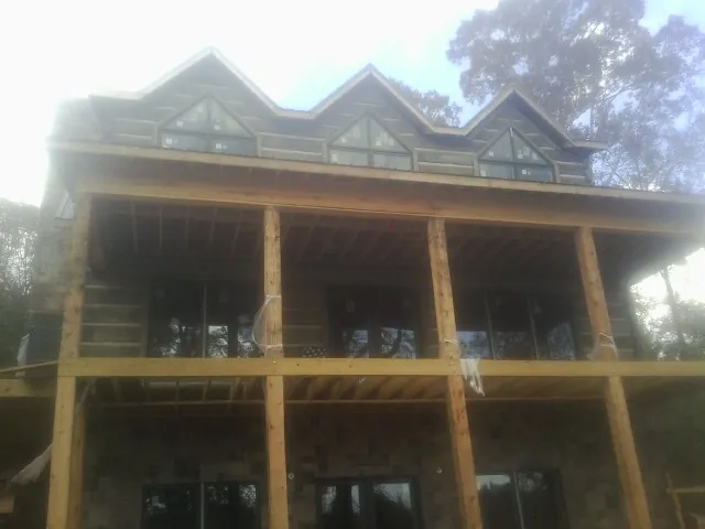 Dormers and porch framing on a large log home under construction — Roof Coating work by our crew in Leasburg