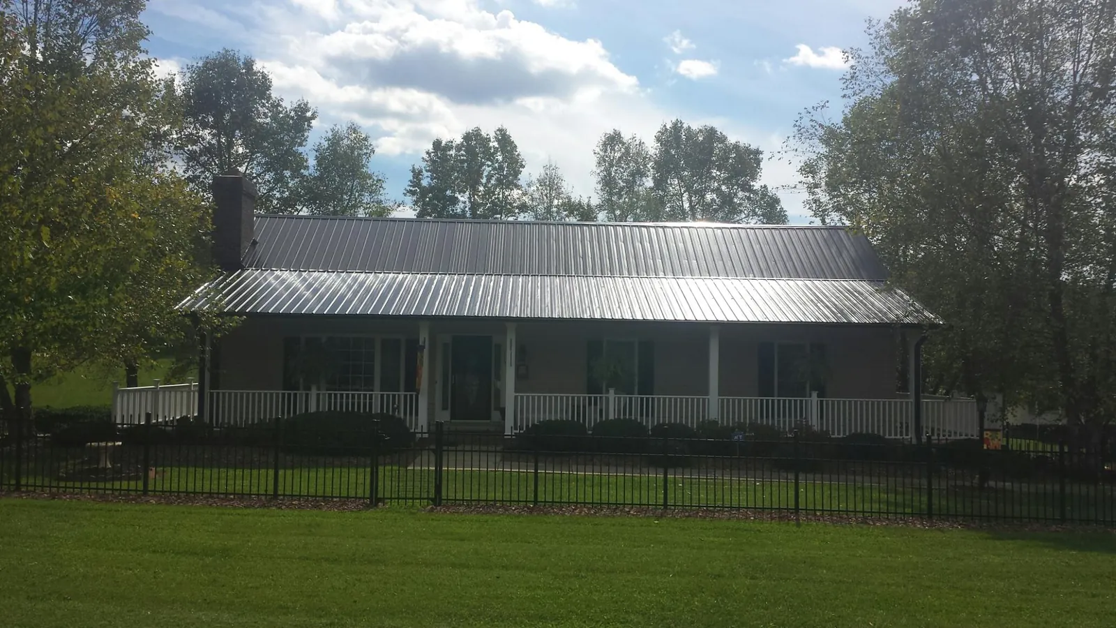 Gray metal roof on a brick ranch with a full width front porch — Gutter Guard Installation work by our crew in Leasburg
